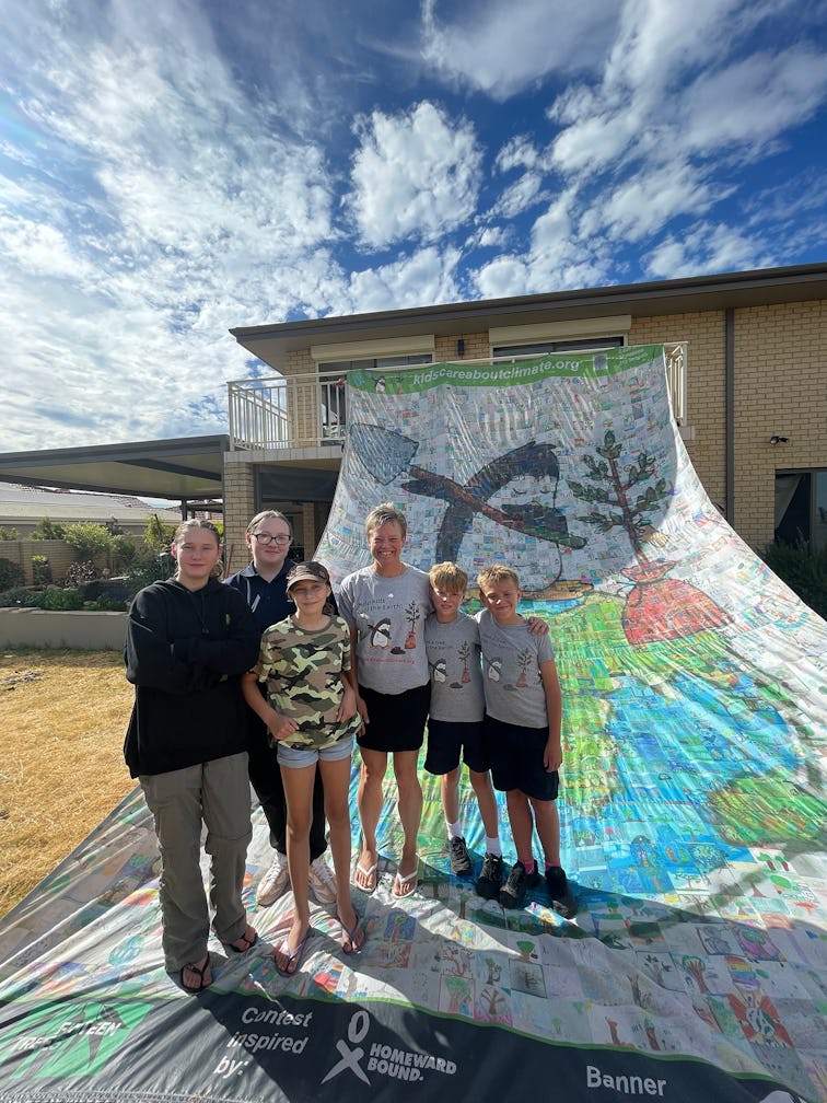 Marji Puotinen (centre) with Millennium Kids and the giant banner for the Kids Care About Climate Change initiative (Image credit Sara Foster)