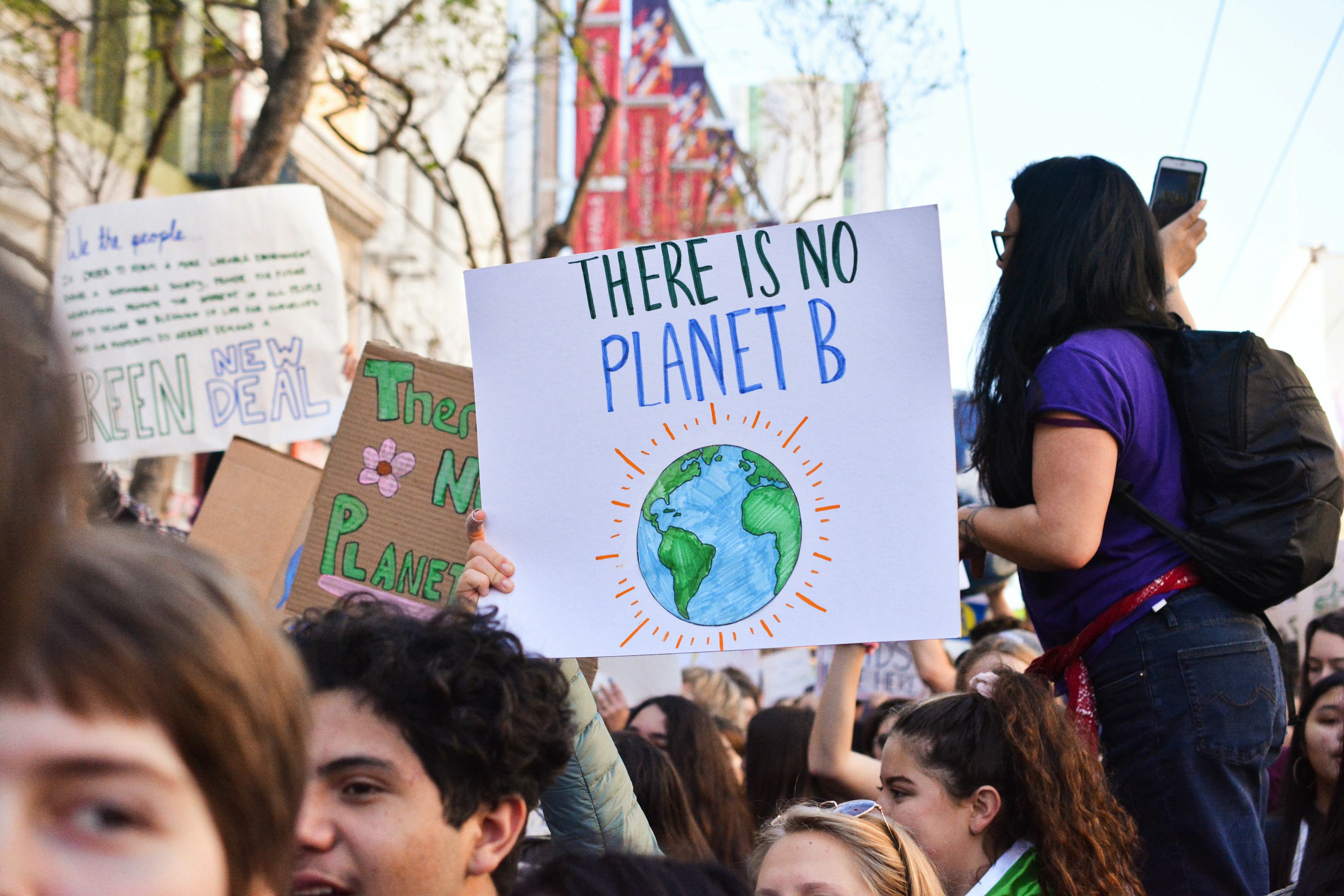 Climate protestors marching through the streets holding signs containing hopeful messages. Image: Li An Lim/Unsplash