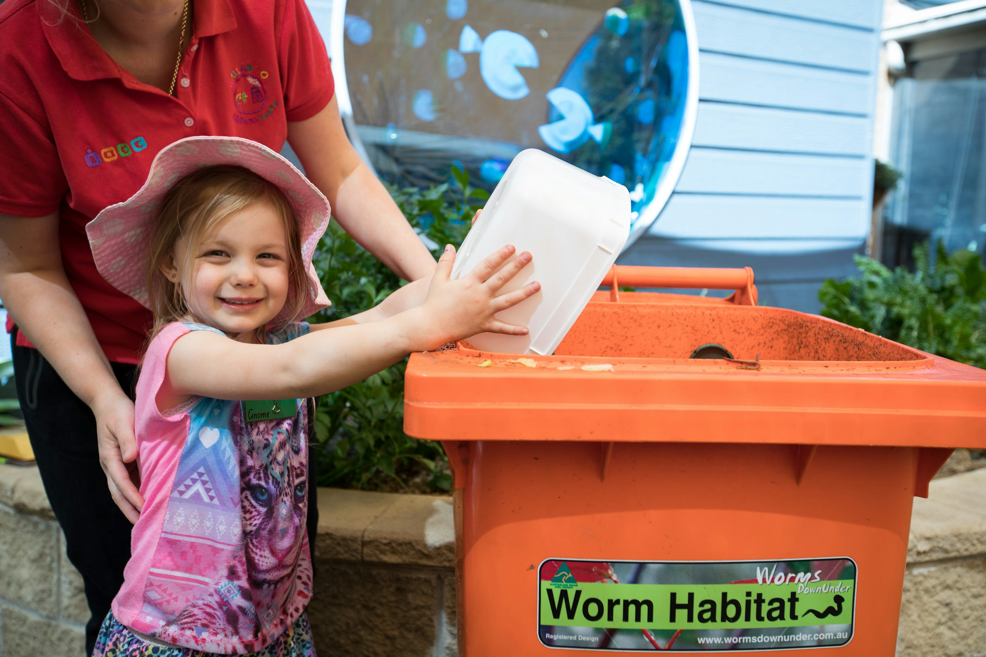 Kid putting food scraps in a worm farm 